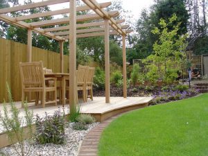 Wooden pergola in garden with wooden table and chairs underneath